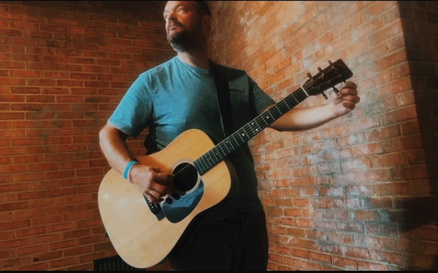 John Leonard playing acoustic guitar